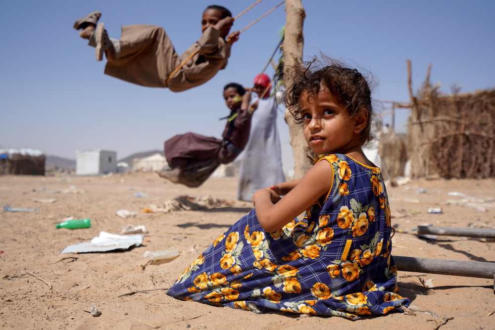 A girl sits as other children play on swings at a camp for internally displaced people in Marib, Yemen Feb. 16, 2021. (Reuters) A girl sits as other children play on swings at a camp for internally displaced people in Marib, Yemen Feb. 16, 2021. (Reuters)