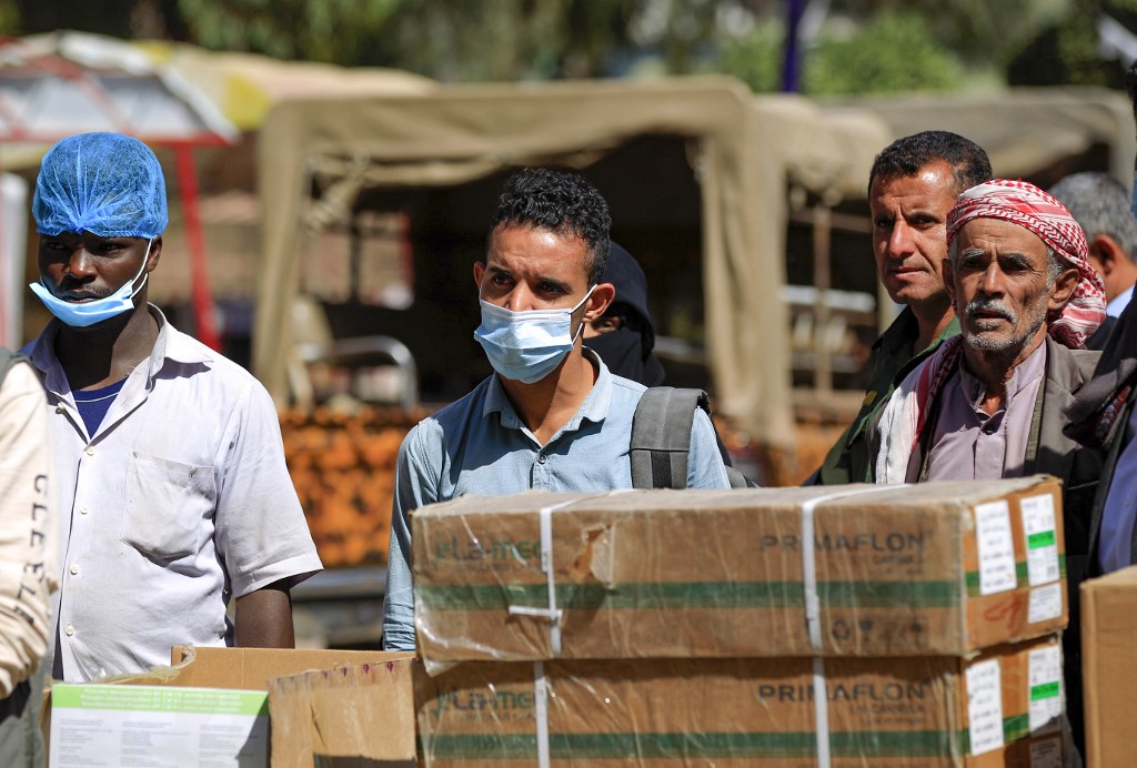 A Yemeni man wearing a protective mask stands among others, waiting for a food aid distribution, in front of a hospital, in the Yemeni capital Sanaa, on March 24, 2021. (File/AFP)