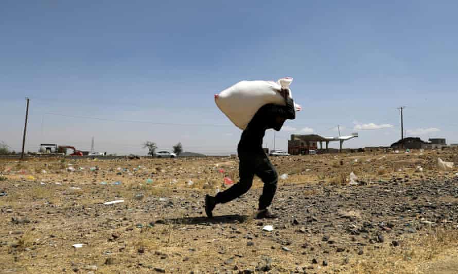 A man carries a sack of flour from the Mona Relief charity at a camp for internally displaced people on the outskirts of Sana’a, Yemen. (Reuters)