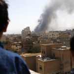 Children look on as smoke billows above the residential area following airstrikes of the Saudi-led coalition targeting Houthi-held military positions on March 7, 2021 in Sanaa, Yemen. (Mohammed Hamoud/Getty Images)
